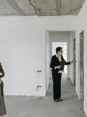 A couple explores an unfinished apartment with a real estate agent, considering property purchase options.