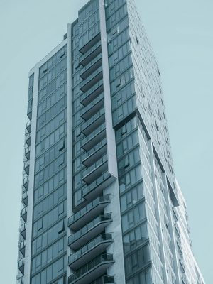 A sleek high-rise building featuring a modern glass facade against a clear blue sky.